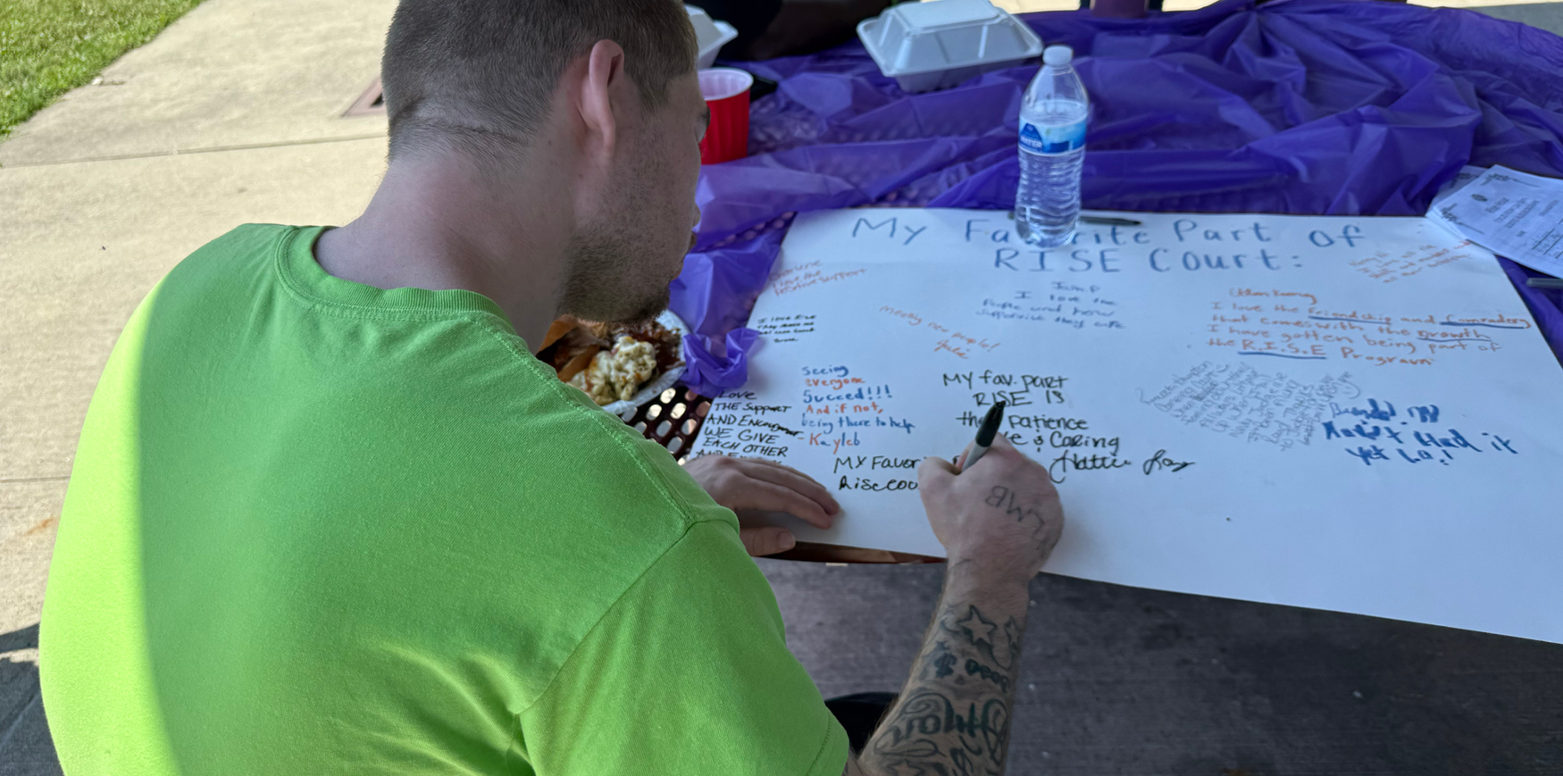 a man drawing on a poster board on a picnic table