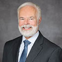 A man wearing a grey suit and blue tie.