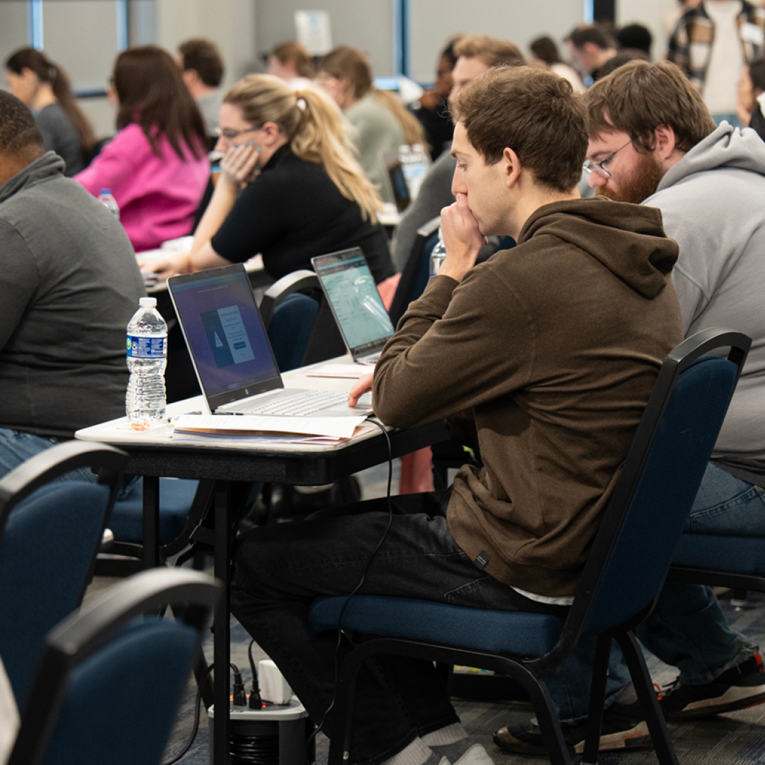 Students sitting at tables reading laptops