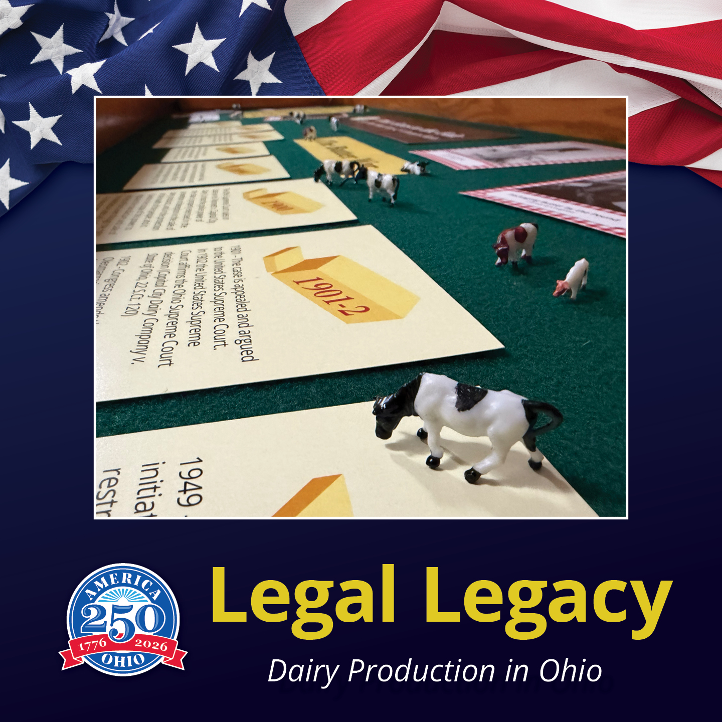 An educational interactive display about Ohio's dairy legal history features a green tabletop layout with historical timeline cards and miniature toy cows.