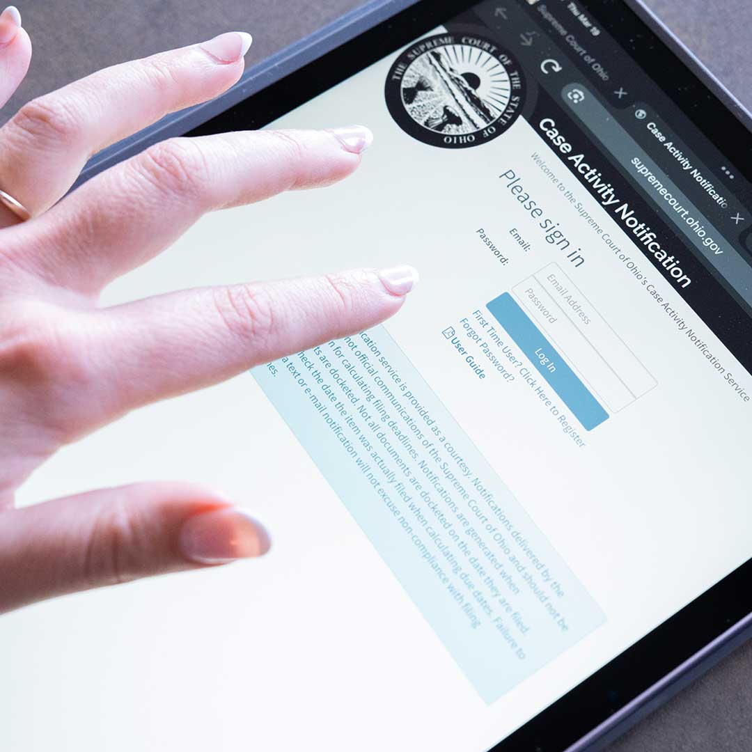 A hand clicking on a tablet screen with a webpage that reads 'Case Activity Notification'