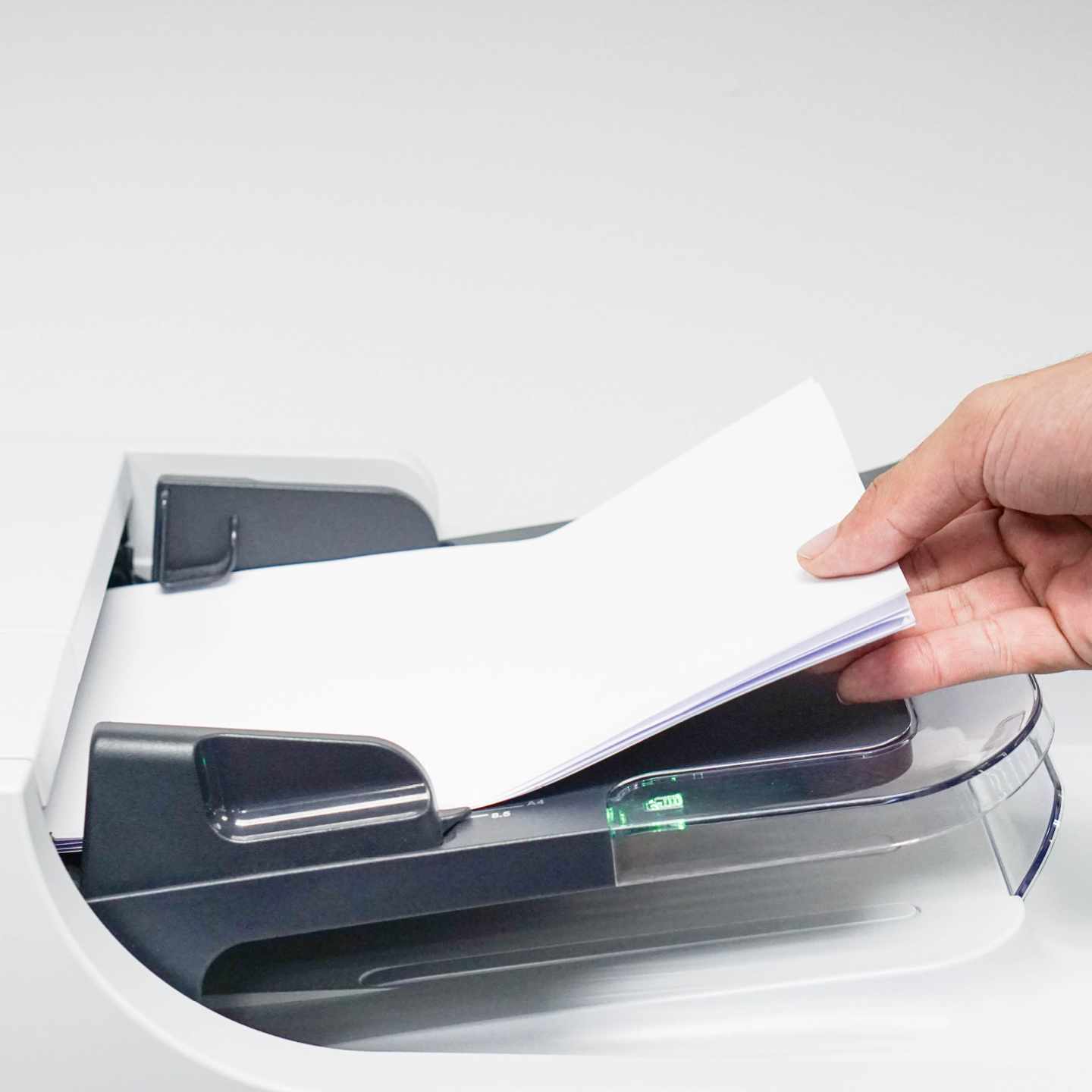 Hand placing a stack of papers into a document scanner.