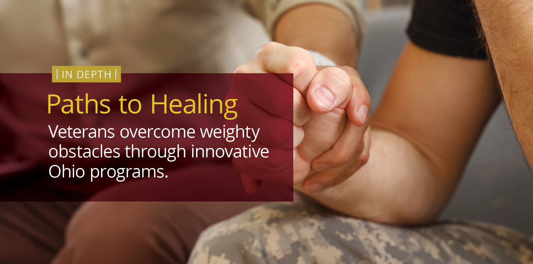 A man wearing camouflage pants and a dark-colored t-shirt grasps the hand of another man wearing brown pants and a long-sleeve khaki shirt.