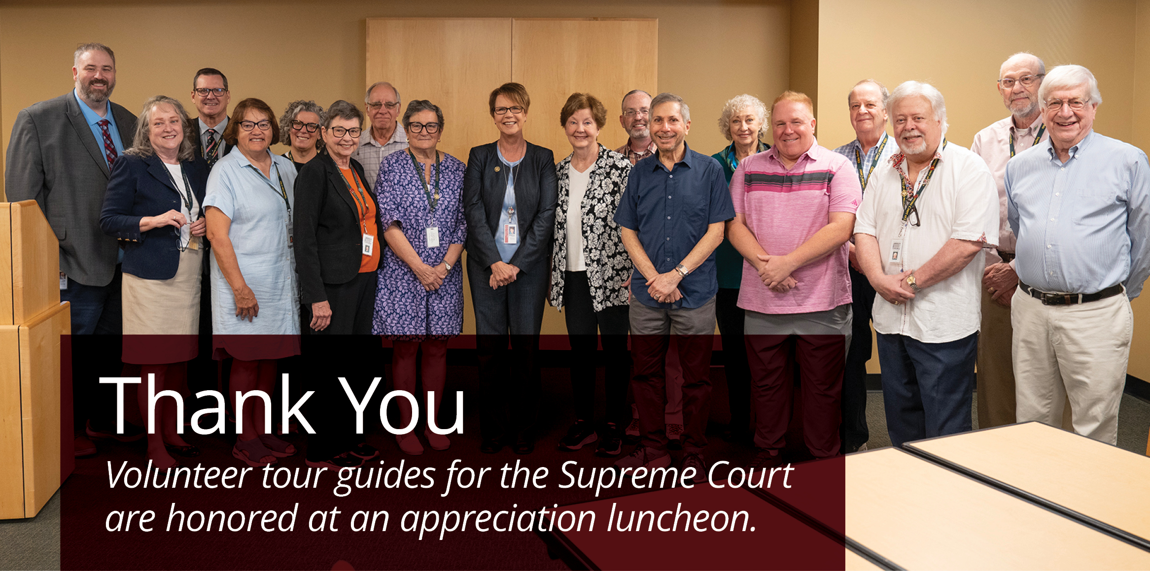 A group of 18 people smiling in a group with text that reads 'Thank you: Volunteer tour guides for the Supreme Court are honored at an appreciation luncheon.'
