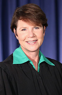 Image of a female judge wearing a black judicial robe and a green blouse.