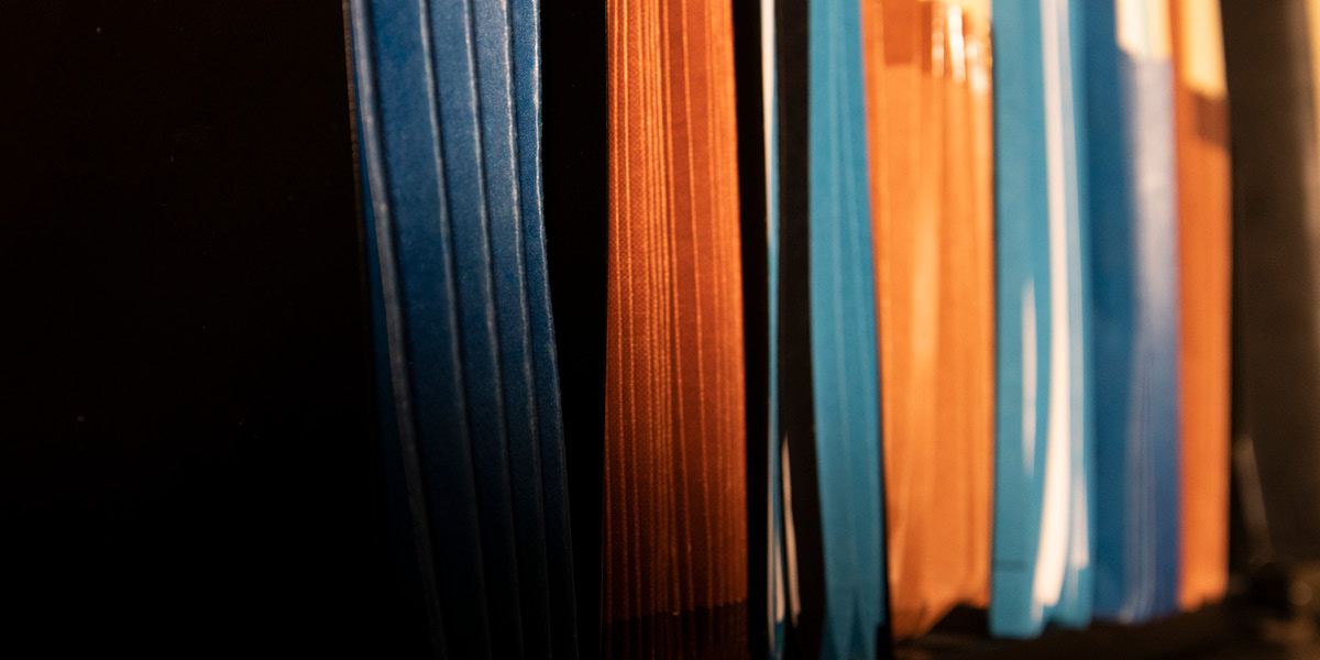 Image of a close-up shot of a horizontal stack of blue and orange file folders.
