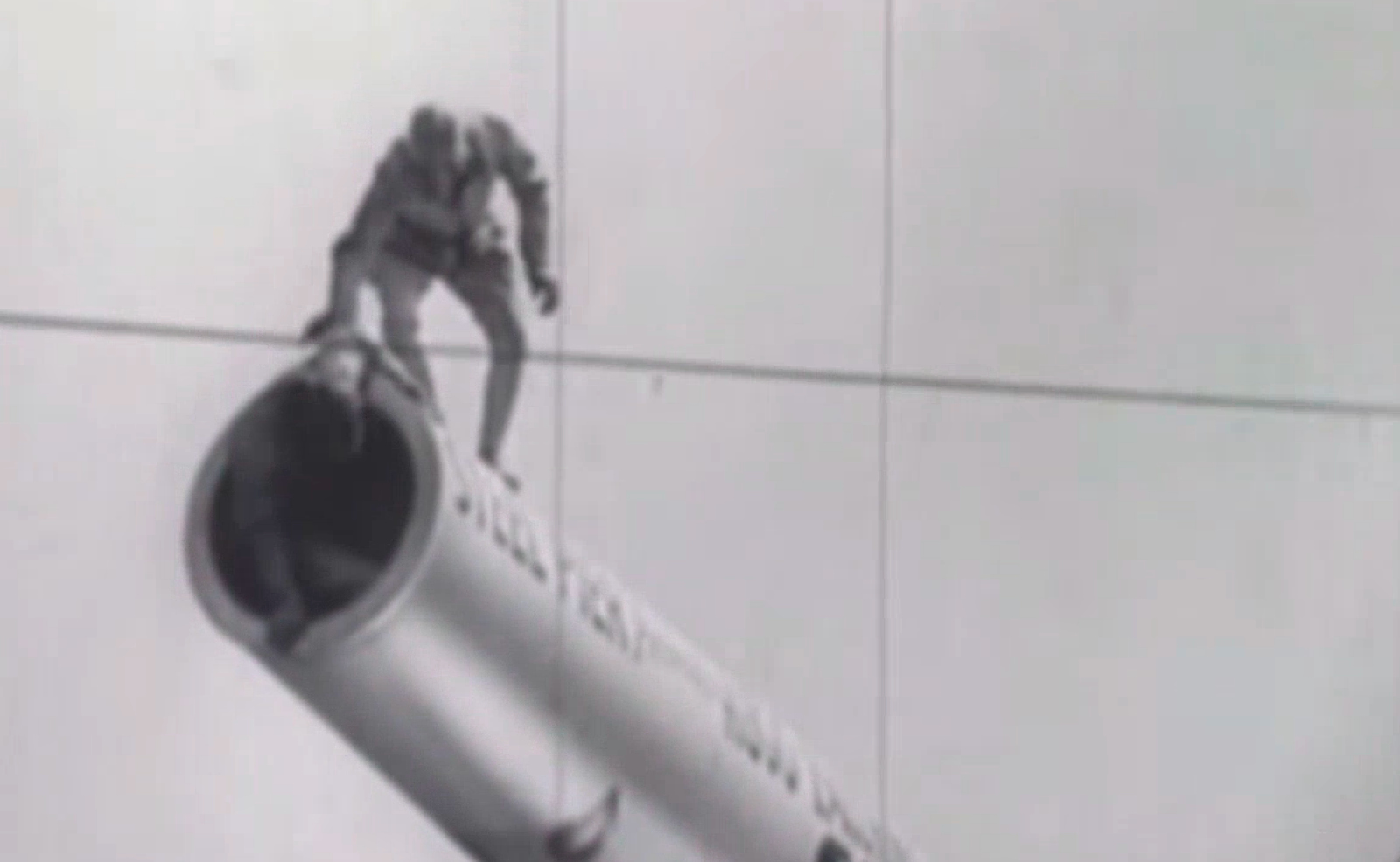 Grainy, black and white image of a man standing on top of a cannon