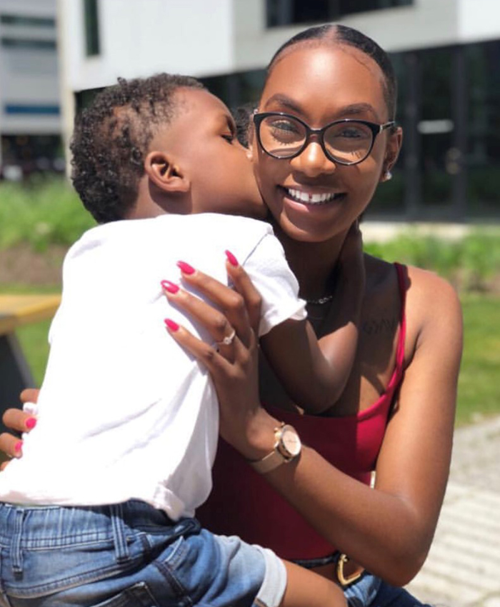 Image of a woman wearing glasses and holding a young boy who is kissing her on the cheek