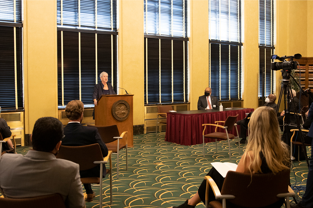 Image of a woman speaking from a podium to a group of people gathered in the law library of the Thomas J. Moyer Ohio Judicial Center