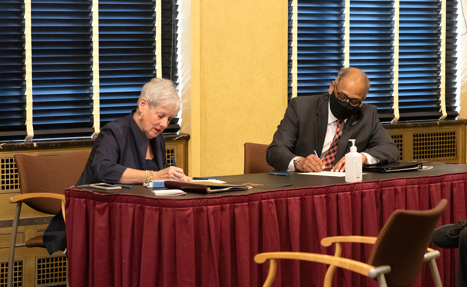 Image of a woman and man sitting at a table each writing on a piece of paper