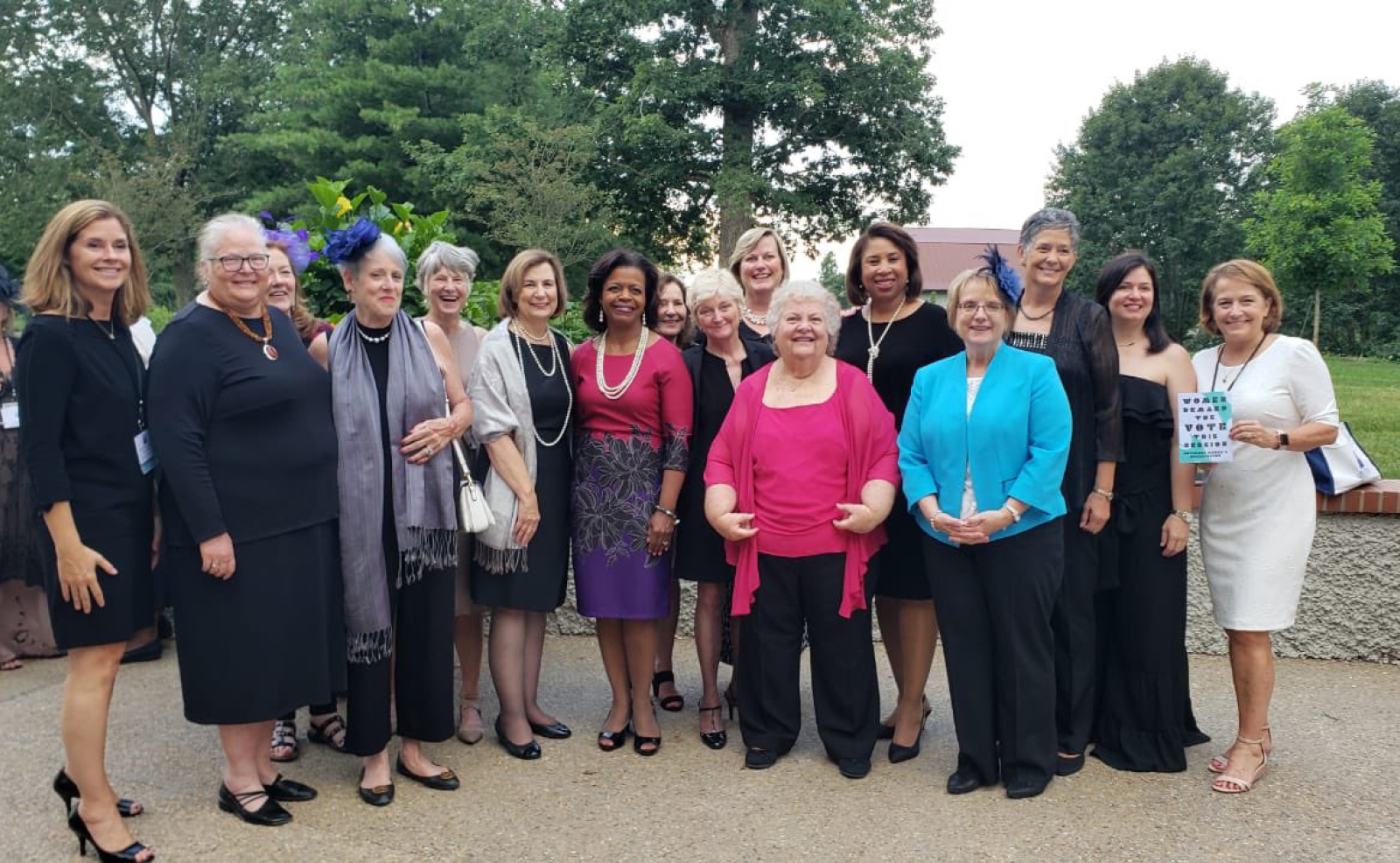 Image of a group of women, some wearing colorful hats, standing outside