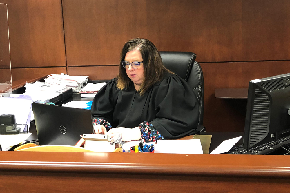 Image of a female judge wearing her black judicial robe using a laptop computer