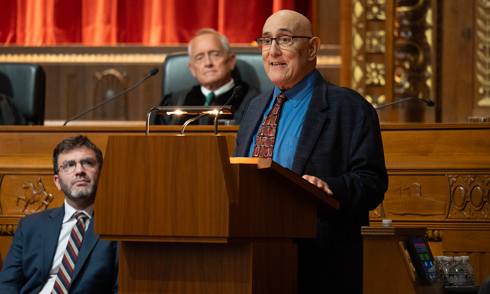 A man speaks from a wooden podium.