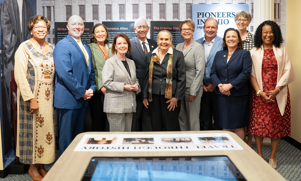 A group of men and women in front of an exhibit.